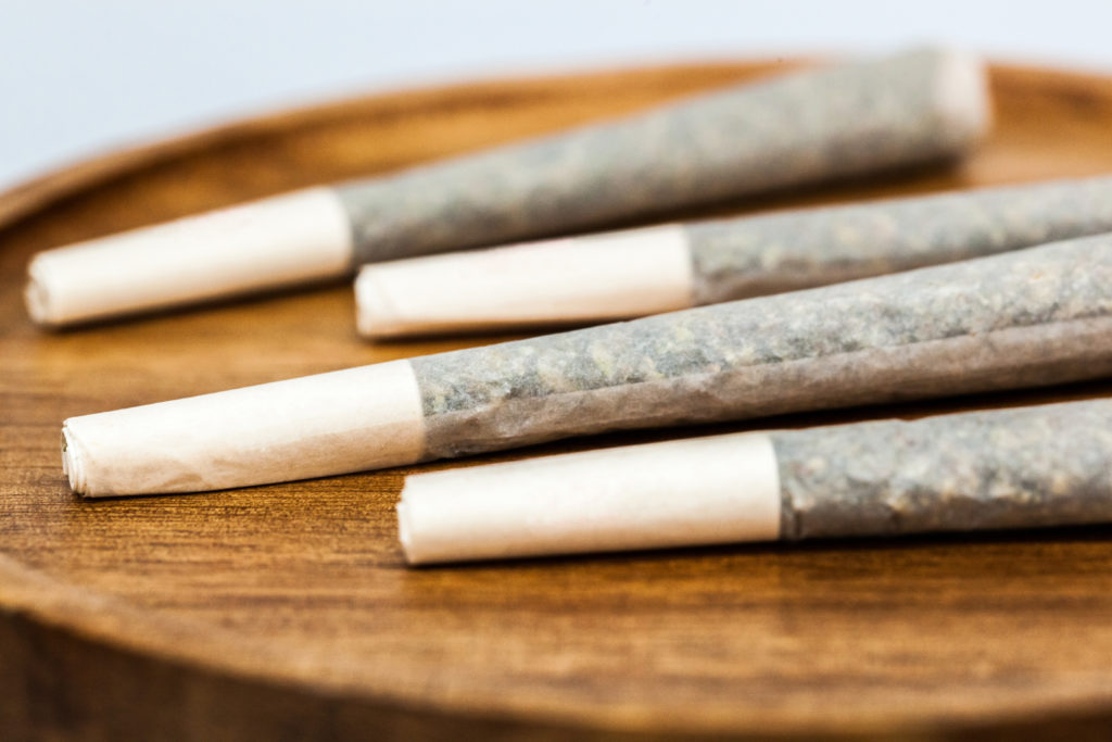 A close up of four pre rolls on a wooden tray